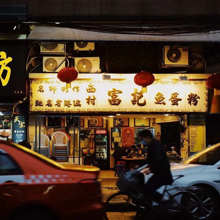 骑车人经过广州一家亮灯的餐饮店