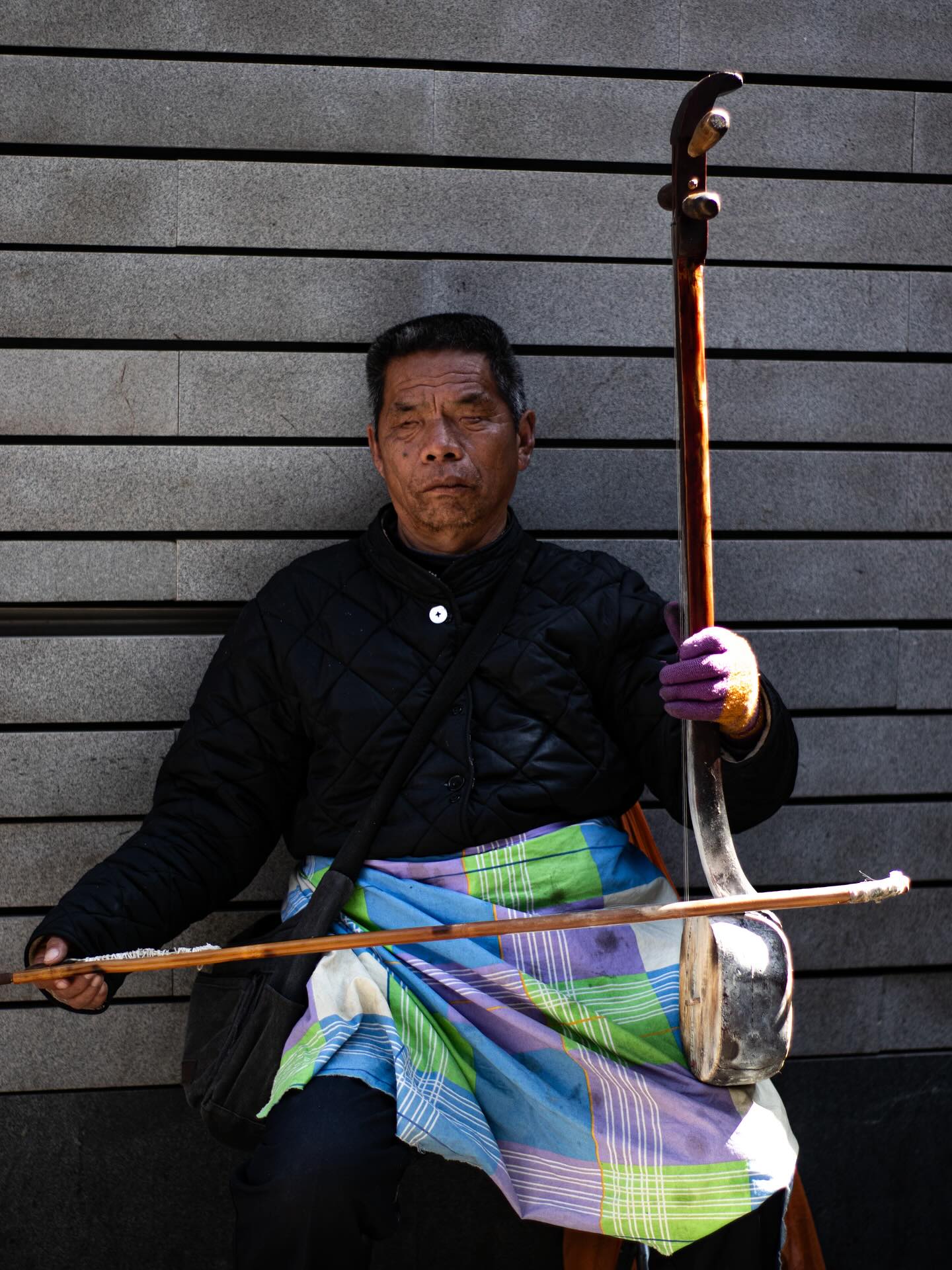 Een zittende muzikant met een strijkinstrument in Beijing